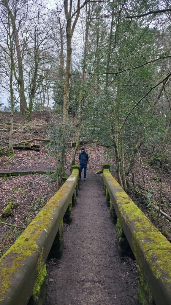 Mężczyzna stojący po drugiej stronie kamiennego mostu.