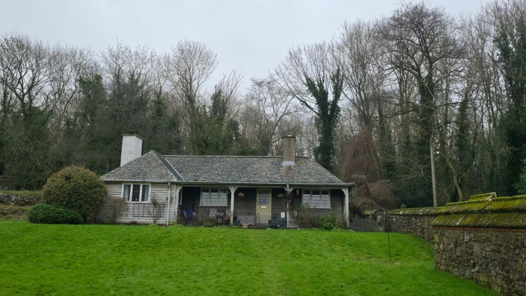 Widok na niewielki domek parterowy z rozbudowanym gankiem.